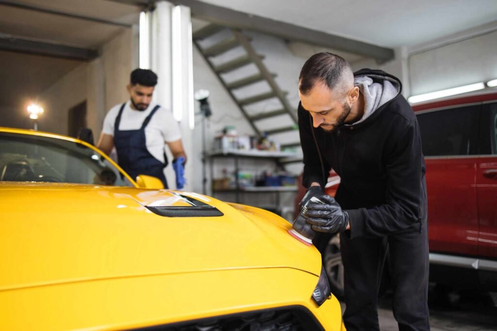 team-of-men-workers-polishing-yellow-car-body-with-B3FUCD9.jpg